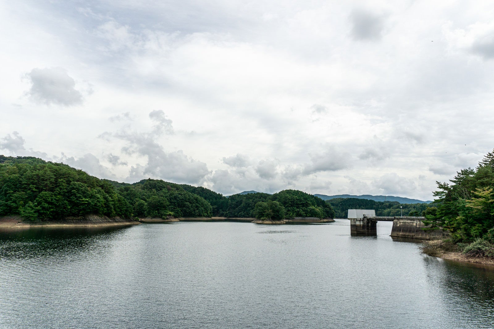「厚い雲に覆われた空の下に広がる黒田ダムによって作られた黒田湖」の写真