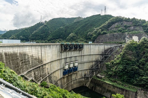 愛知県豊田市（左岸・画面奥）と岐阜県恵那市（右岸・画面手前）にまたがる巨大なアーチ式コンクリート型式の矢作)ダムの写真