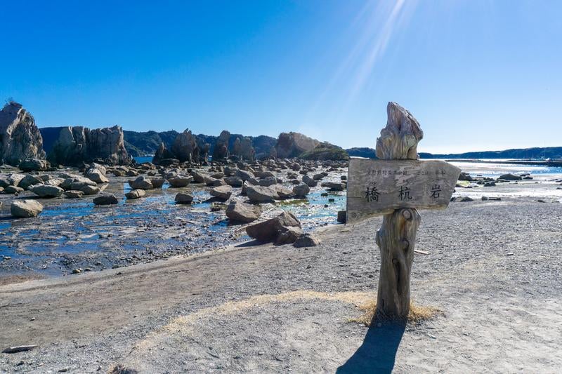 青空と透き通る潮溜まりに囲まれた橋杭岩の写真