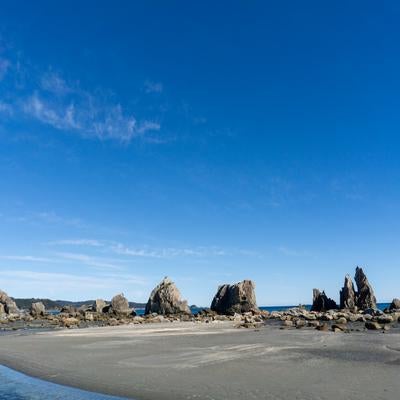 干潮時に現れる広い砂浜と一直線に並ぶ橋杭岩の写真