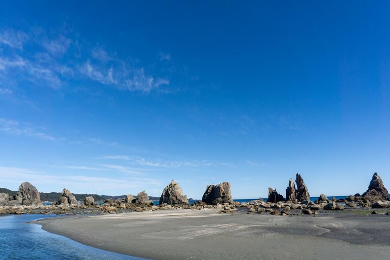 干潮時に現れる広い砂浜と一直線に並ぶ橋杭岩の写真