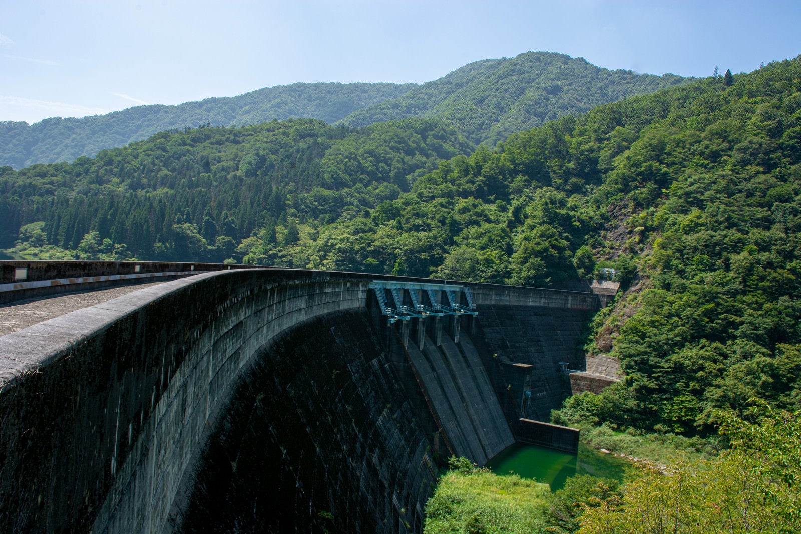 「右岸から見る日本に11基しか存在しない重力式アーチダムの鷲ダムの姿」の写真
