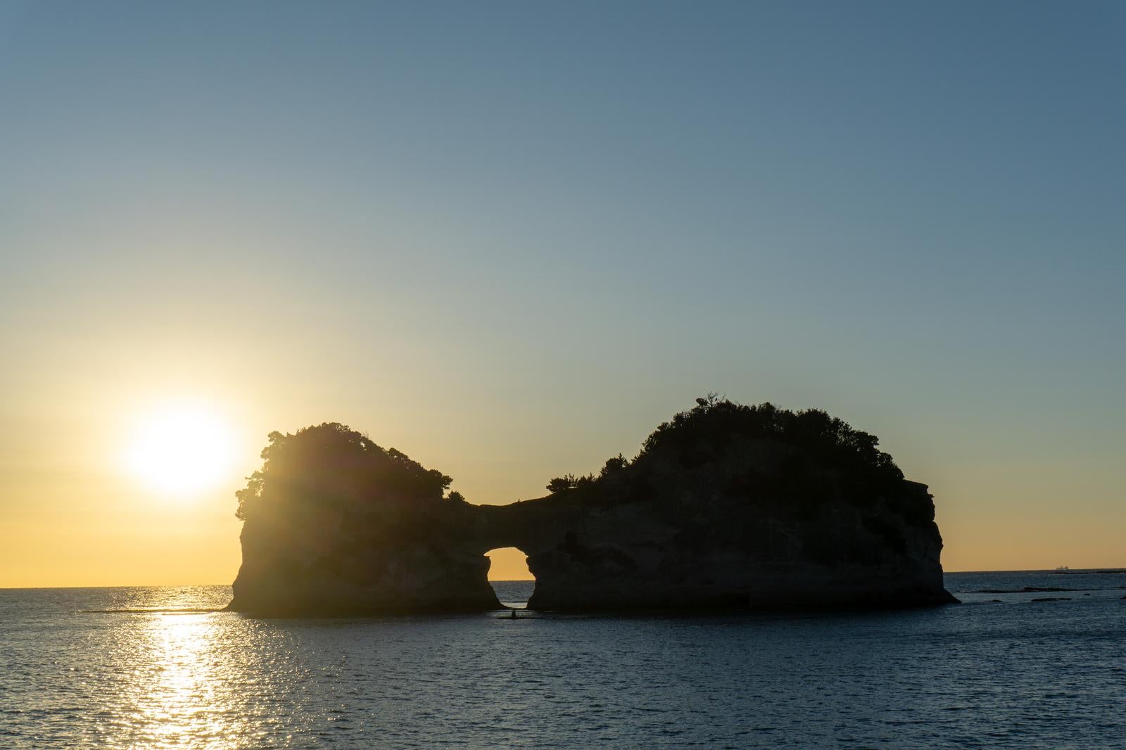 「夕日に照らされる円月島と光の道」の写真
