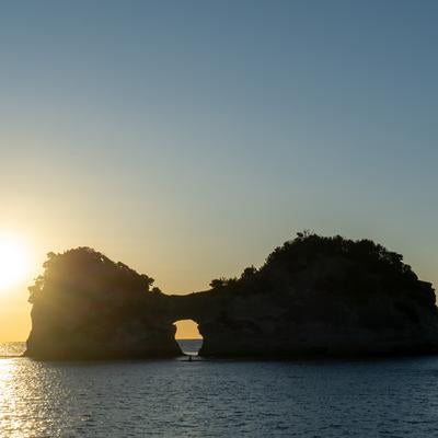 夕日に照らされる円月島と光の道の写真