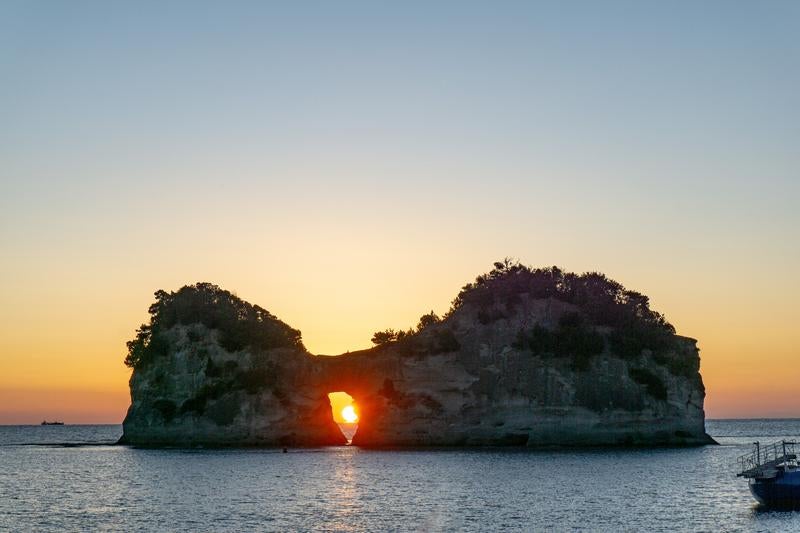円月島の穴に沈む夕陽の写真