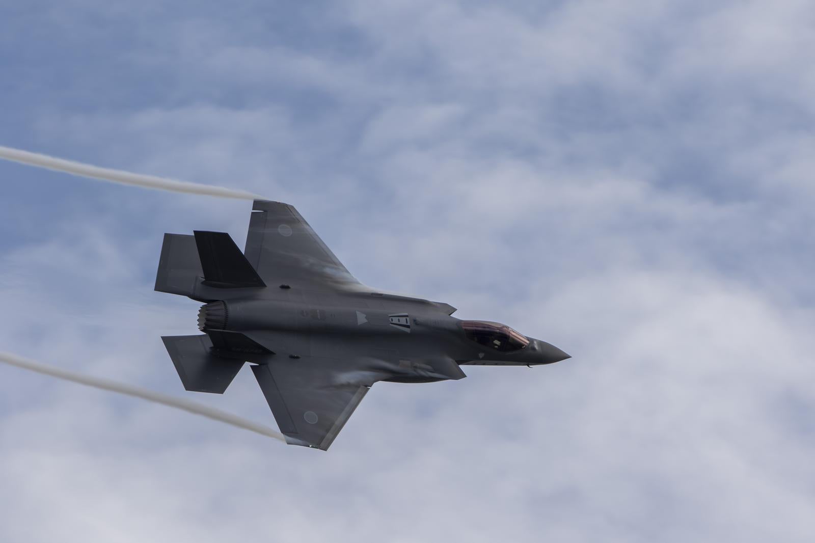 曇り空を背景に飛行する航空自衛隊のF-35Aライトニング戦闘機