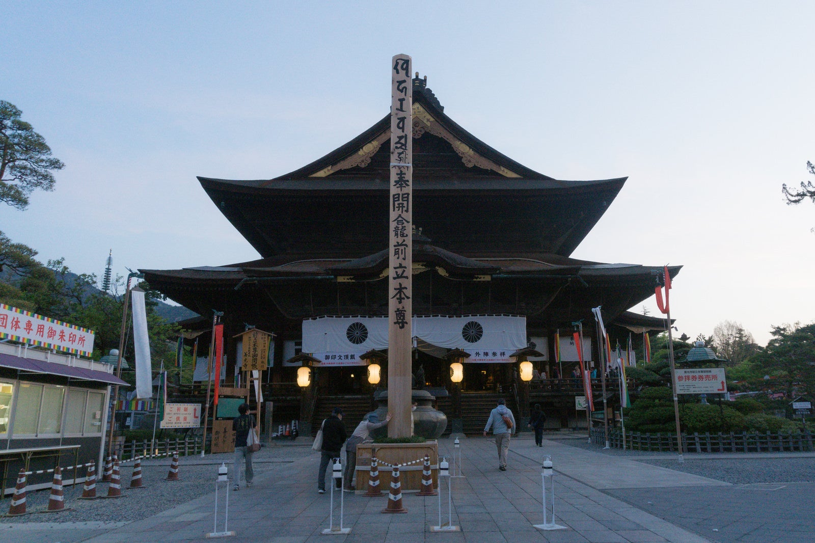 「御開帳で回向柱（えこうばしら）が立つ、まだお燈明が灯る夜明け直後の善光寺本堂前」の写真