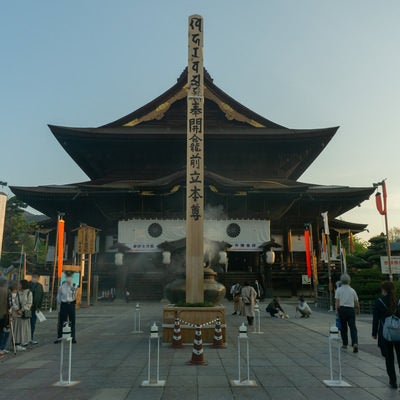 善光寺本堂とその前に立つ約45センチ角高さ約10メートルの善光寺御開帳のシンボルとも言える回向柱の写真