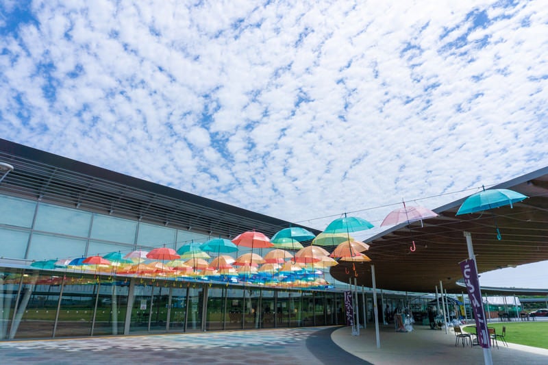 カラフルな傘の列とひつじ雲の空の写真