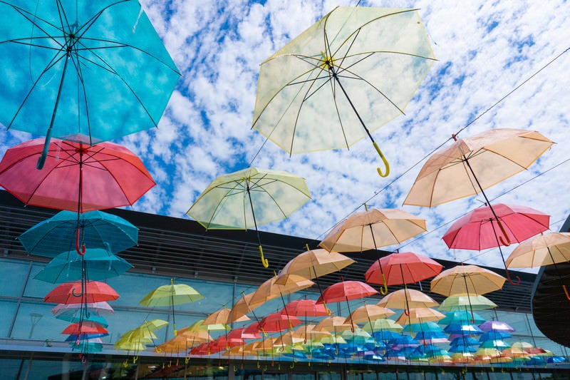 梅雨の合間の晴れた空に並ぶたくさんのカラフルな傘（道の駅パレットピアおおの 岐阜県）の写真