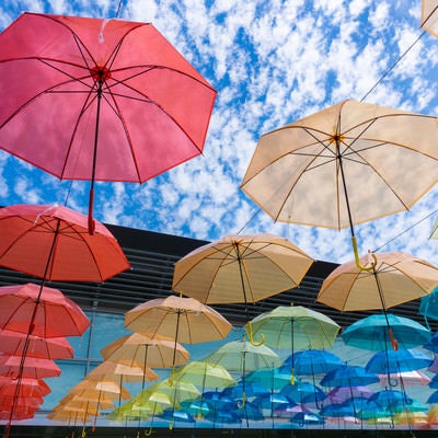 細かな模様を描く美しい空ときれいに並ぶ色とりどりの傘の写真